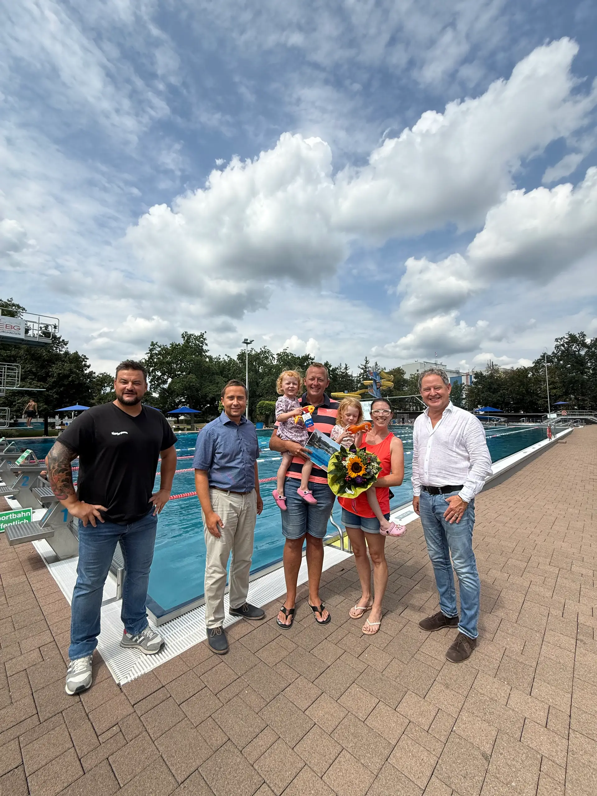 Familie aus Ampfing als 100.000. Badegast im Burghauser Freibad mit Blumen, Taucherbrillen und Familien-Saisonkarte.