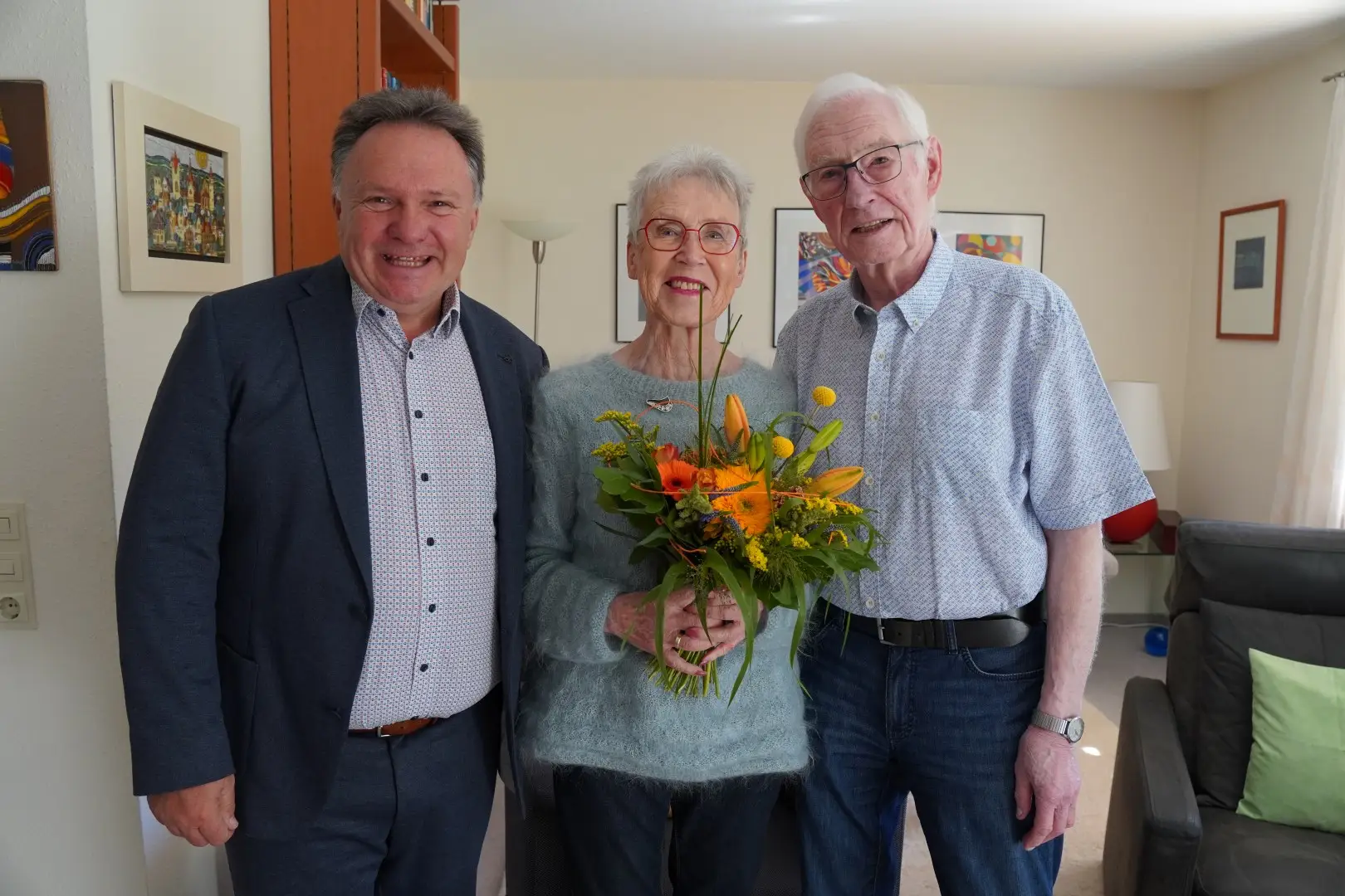 Zwei Personen, Rosmarie und Horst Lauerwald, stehen bei einem Besuch anlässlich ihres 60. Hochzeitstags; Oberbürgermeister Stefan Bosse steht links und gratuliert.